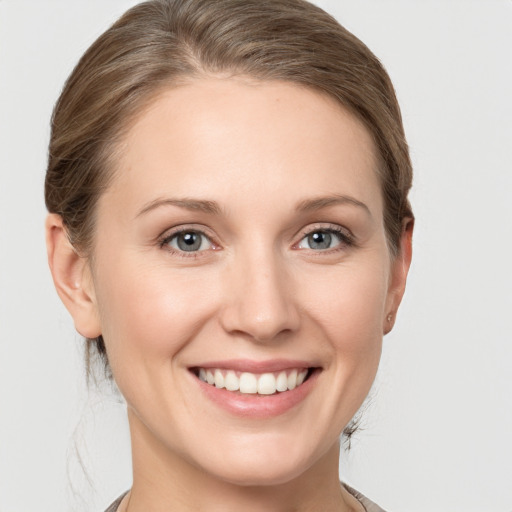 Joyful white young-adult female with medium  brown hair and grey eyes