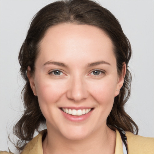 Joyful white young-adult female with medium  brown hair and grey eyes