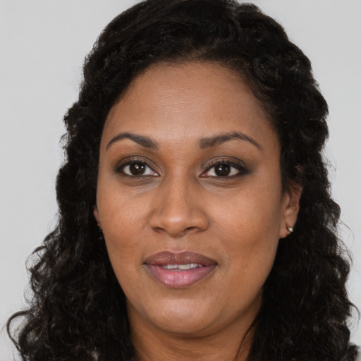 Joyful black adult female with long  brown hair and brown eyes