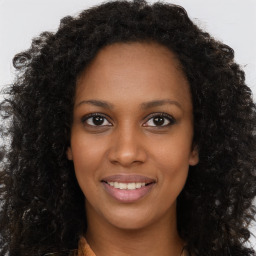 Joyful black young-adult female with long  brown hair and brown eyes