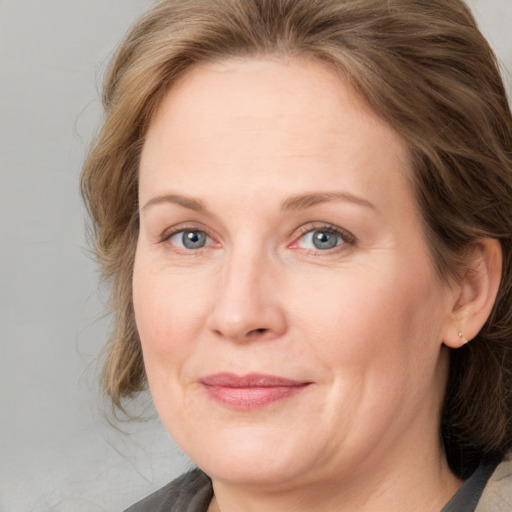 Joyful white adult female with medium  brown hair and blue eyes