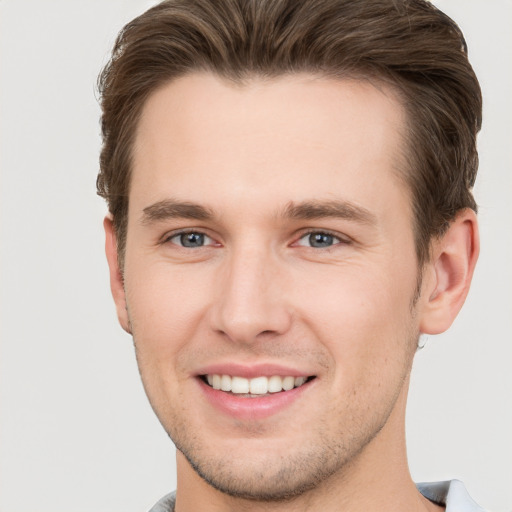 Joyful white young-adult male with short  brown hair and grey eyes