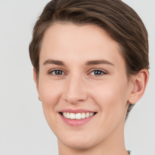 Joyful white young-adult female with short  brown hair and grey eyes