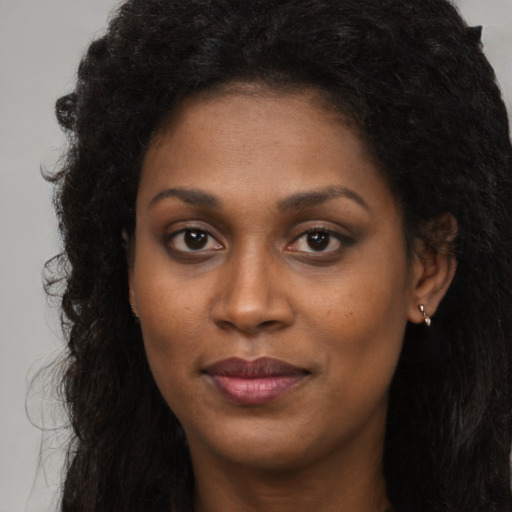 Joyful black young-adult female with long  brown hair and brown eyes
