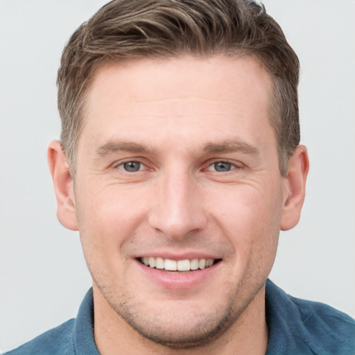 Joyful white young-adult male with short  brown hair and grey eyes