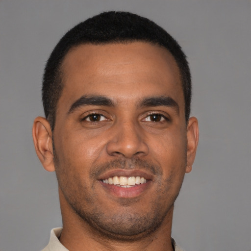 Joyful black young-adult male with short  brown hair and brown eyes