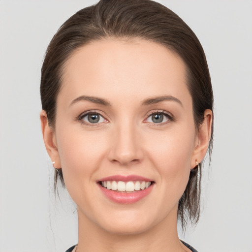 Joyful white young-adult female with medium  brown hair and grey eyes