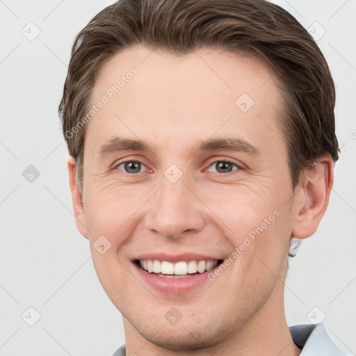 Joyful white young-adult male with short  brown hair and grey eyes