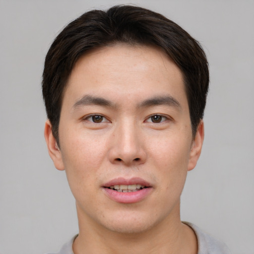 Joyful asian young-adult male with short  brown hair and brown eyes