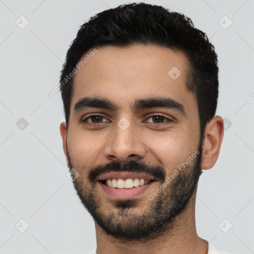 Joyful latino young-adult male with short  black hair and brown eyes