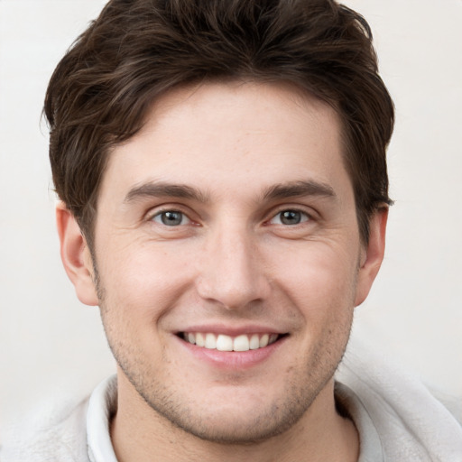 Joyful white young-adult male with short  brown hair and grey eyes