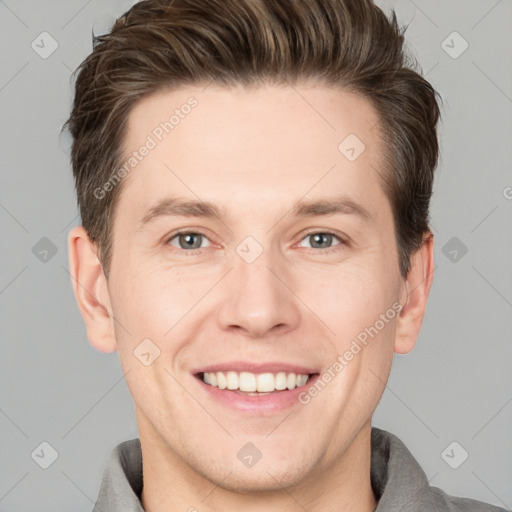 Joyful white young-adult male with short  brown hair and grey eyes