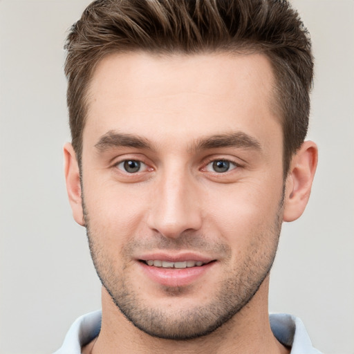 Joyful white young-adult male with short  brown hair and grey eyes