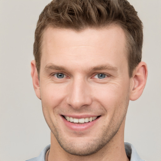 Joyful white young-adult male with short  brown hair and grey eyes