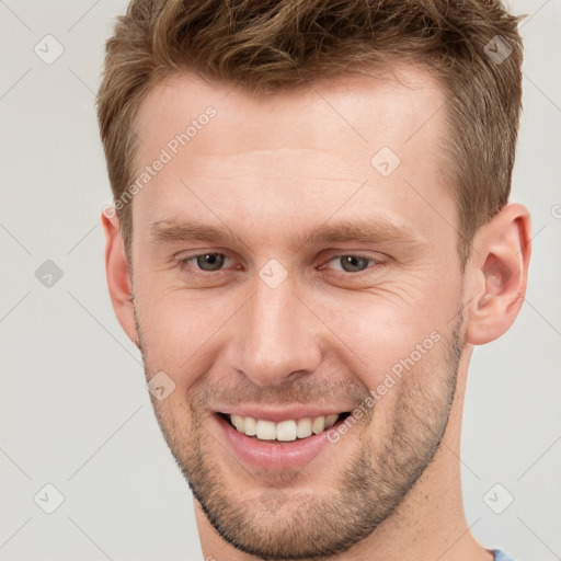 Joyful white young-adult male with short  brown hair and grey eyes