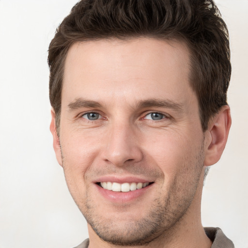 Joyful white young-adult male with short  brown hair and grey eyes