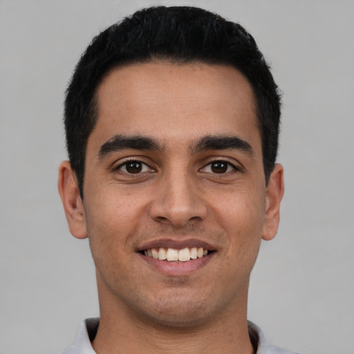 Joyful latino young-adult male with short  black hair and brown eyes