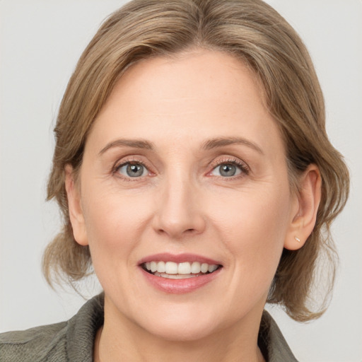 Joyful white adult female with medium  brown hair and grey eyes