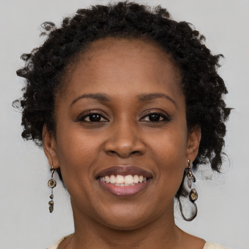 Joyful black young-adult female with long  brown hair and brown eyes