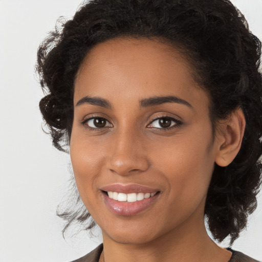 Joyful black young-adult female with long  brown hair and brown eyes