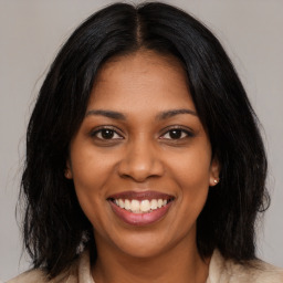 Joyful black young-adult female with long  brown hair and brown eyes