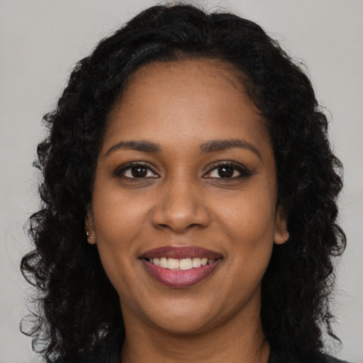 Joyful black young-adult female with long  brown hair and brown eyes