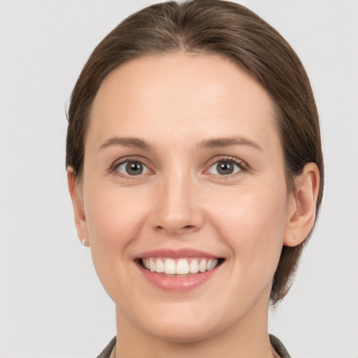 Joyful white young-adult female with medium  brown hair and grey eyes