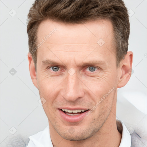 Joyful white adult male with short  brown hair and grey eyes