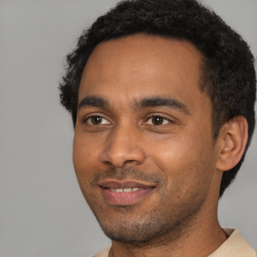 Joyful black young-adult male with short  black hair and brown eyes