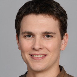 Joyful white young-adult male with short  brown hair and grey eyes