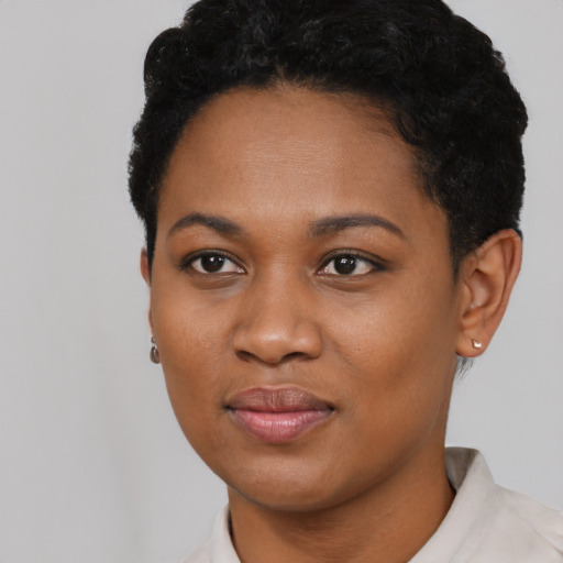 Joyful black young-adult female with short  black hair and brown eyes
