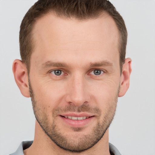 Joyful white young-adult male with short  brown hair and grey eyes