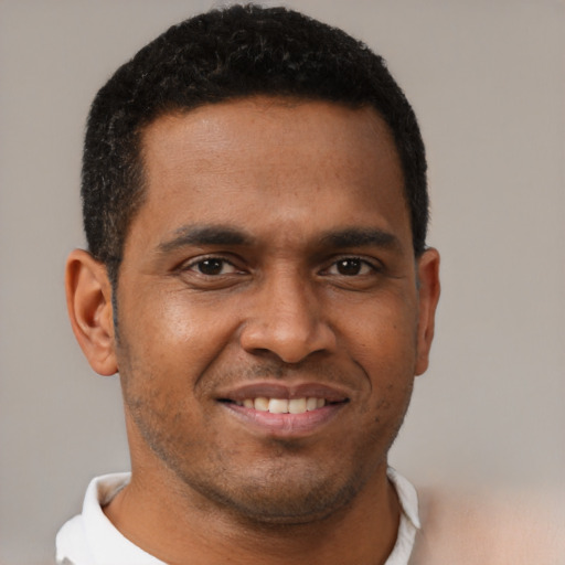 Joyful black young-adult male with short  brown hair and brown eyes