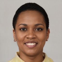 Joyful black young-adult female with short  black hair and brown eyes