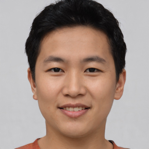 Joyful asian young-adult male with short  black hair and brown eyes