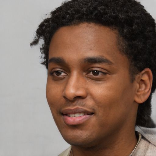 Joyful black young-adult male with short  black hair and brown eyes