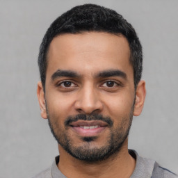 Joyful latino young-adult male with short  black hair and brown eyes