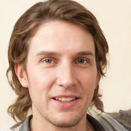 Joyful white young-adult male with medium  brown hair and grey eyes