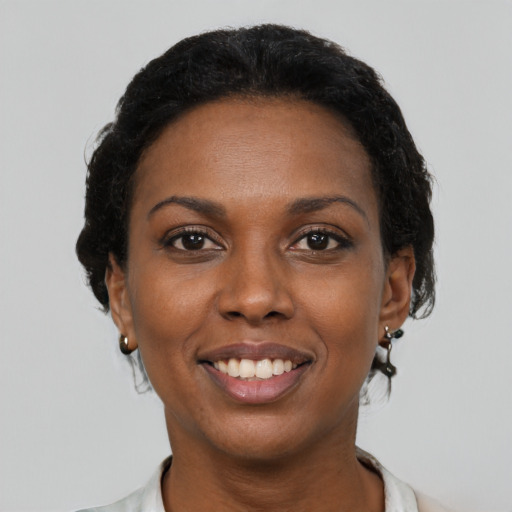 Joyful black young-adult female with short  black hair and brown eyes