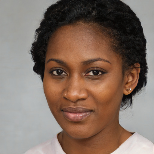 Joyful black young-adult female with short  black hair and brown eyes