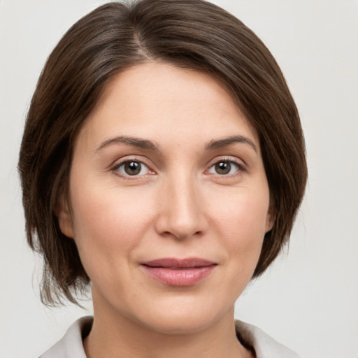 Joyful white young-adult female with medium  brown hair and grey eyes