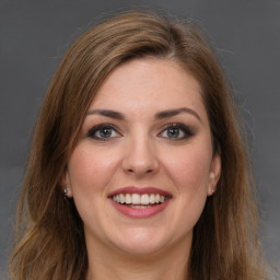 Joyful white young-adult female with long  brown hair and grey eyes