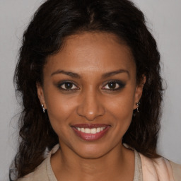 Joyful black young-adult female with long  brown hair and brown eyes