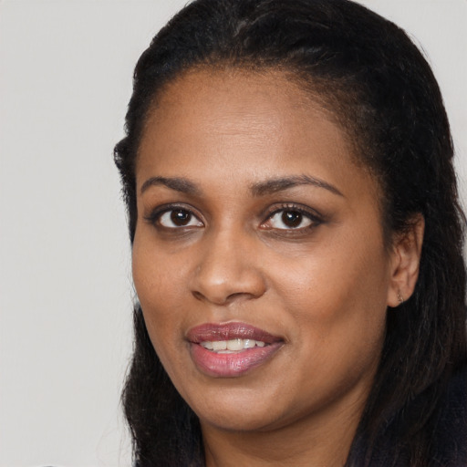 Joyful black young-adult female with long  brown hair and brown eyes