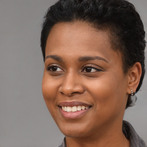 Joyful black young-adult female with short  brown hair and brown eyes