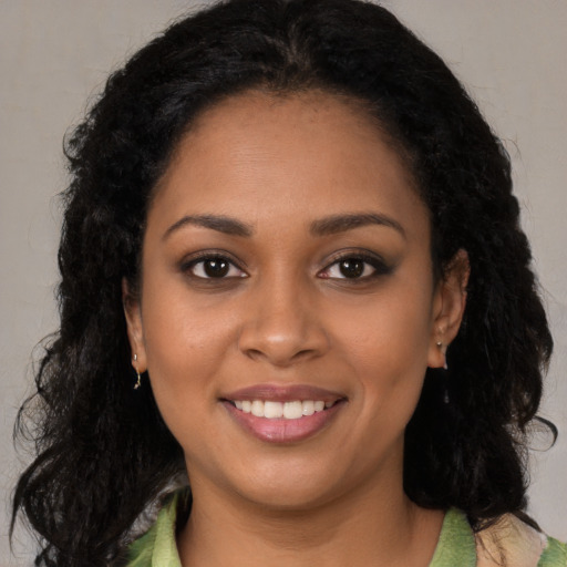 Joyful black young-adult female with long  brown hair and brown eyes