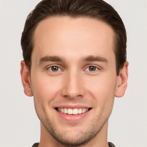 Joyful white young-adult male with short  brown hair and grey eyes