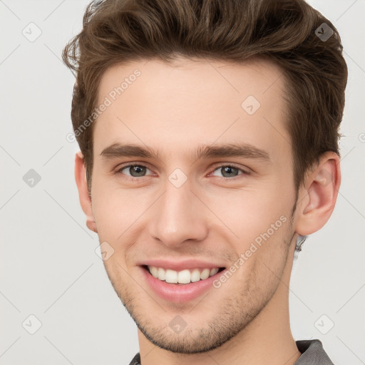 Joyful white young-adult male with short  brown hair and grey eyes