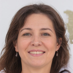 Joyful white adult female with long  brown hair and grey eyes