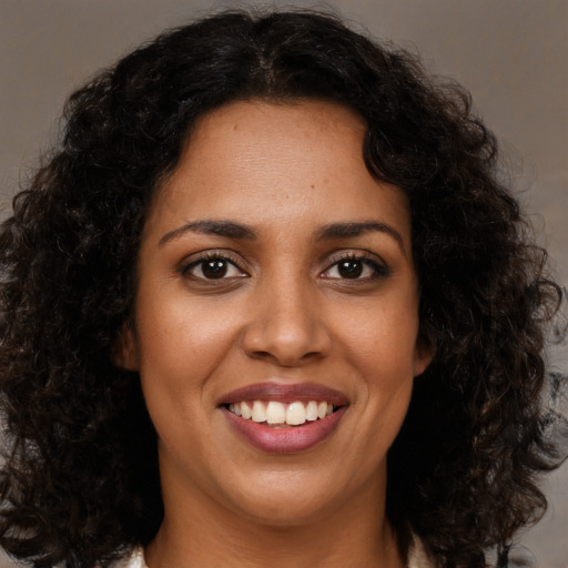 Joyful black young-adult female with long  brown hair and brown eyes